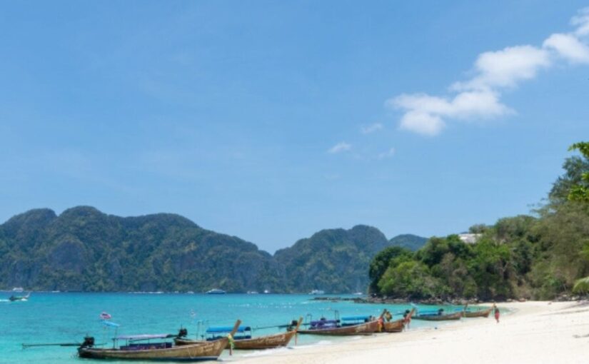 タイ・ピピ島関連ツアーで人気の美しいビーチと伝統的なロングテールボートの風景。