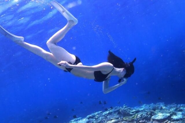 プーケットの離島でシュノーケリングを楽しむ女性。透明度の高い青い海の中に広がる美しいサンゴ礁。