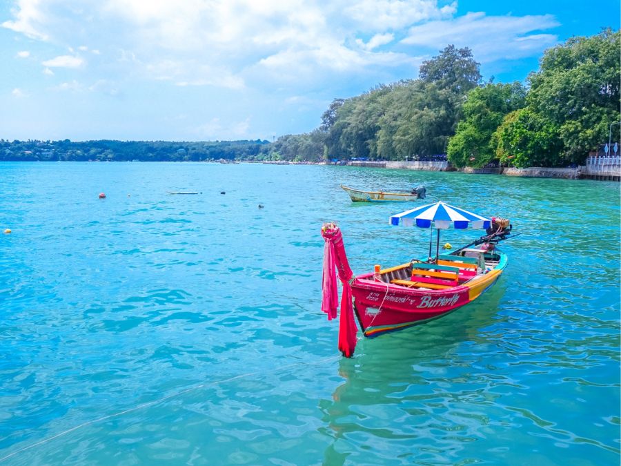 プーケット日本人ガイド同行ツアーで訪れる、透明度の高い海と伝統的なボートが並ぶ美しい海岸風景。