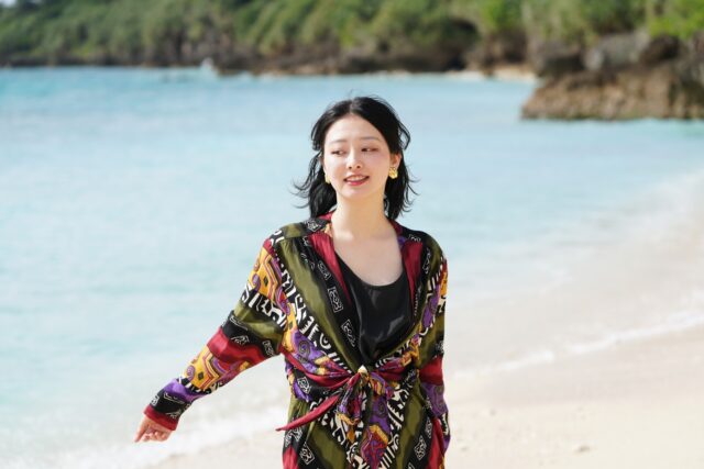 以澄澈的大海和沙滩为背景,一位女性尽情享受度假时光的人像照